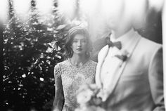 a man and woman standing next to each other in front of a tree with flowers