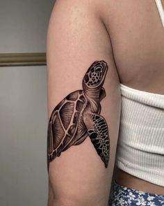 a woman's arm with a tattoo of a turtle on the back of it