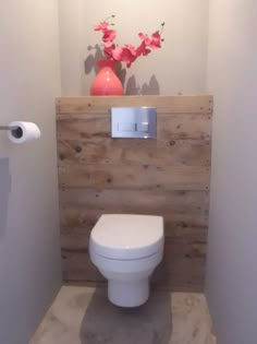 the bathroom is decorated with wood planks and has a white toilet in front of it