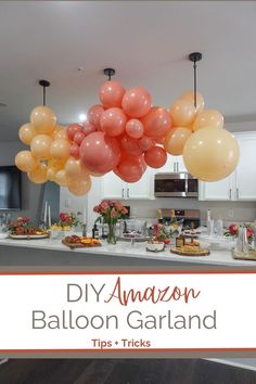 balloons are hanging from the ceiling above a kitchen counter with flowers and cake on it