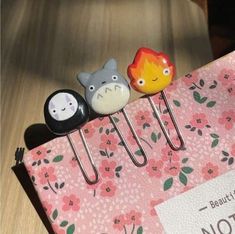 three little pins sitting on top of a pink bag