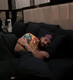 a man laying on top of a bed covered in black sheets