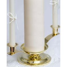 three white candles are on a gold plated stand