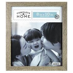 two adults and a child kissing each other in front of a wooden frame with the words complete home written on it