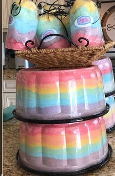 three colorful containers stacked on top of each other in front of a kitchen counter with a clock