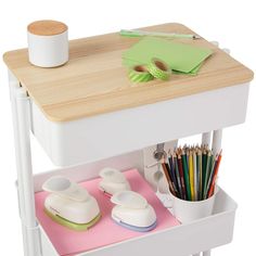 a wooden table topped with lots of crafting supplies next to a cup and pencils