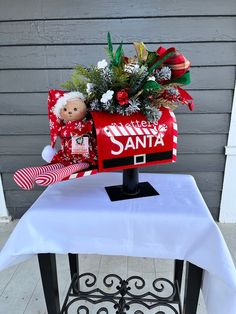 a mailbox decorated with christmas decorations sits on top of a white tablecloth covered bench