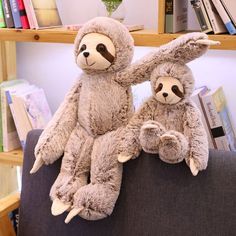 two stuffed slots sitting on top of a couch in front of bookshelves