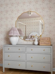 a white dresser topped with a mirror next to a lamp