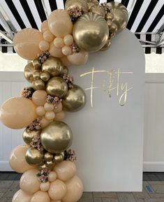 the balloon arch is decorated with gold and white balloons