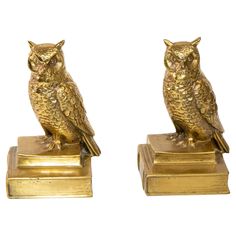 two gold colored owl figurines sitting on top of each other's bases