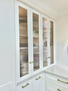 a kitchen with white cabinets and gold handles on the doors is pictured in this image