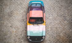 an overhead view of a car painted in multi - colored stripes on cobblestone