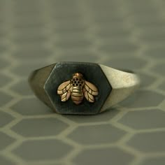 Honey Bee Signet Ring Gold Honeybee Ring Queen Bee Unique Engagement Ring Promise Ring Hexagon Ring Insect Ring Honey Comb Geometric Ring Dimensions: 9mm wide at front tapering to 1.8mm in back; Bee measures 5.5mm tall by 7mm wide; signet area measures 9mm wide by 11.5mm across Materials: .925 Sterling Silver; 14K Gold I had to keep the first one of this design! I love it sooooo much and wear it so often. It goes with everything! It's petite enough to not be overwhelming, but large enough to be Insect Ring, Signet Ring Gold, Cool Rings For Men, Hexagon Ring, Hexagonal Ring, Bee Ring, Cool Rings, Masonic Ring, Tattoo Henna