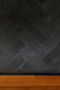 a cat sitting on top of a wooden bench next to a black tile flooring