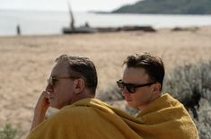 two men wrapped in yellow towels on the beach