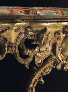 an ornately decorated table with gold paint on it's sides and intricate carvings