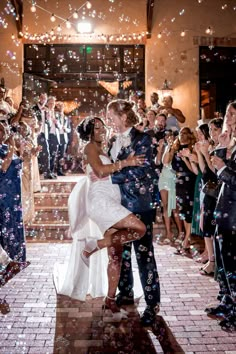 a bride and groom are surrounded by confetti as they dance on their wedding day