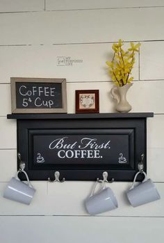 there is a coffee sign on the wall with three cups hanging from it's hooks