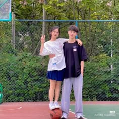 two people standing on a basketball court with trees in the backgrouds behind them