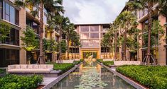 an outdoor pool surrounded by water lilies and greenery in front of a building