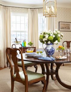 a dining room table and chairs with flowers in vases on the top one side