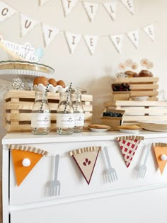 an assortment of desserts are displayed on a buffet with bunting flags and wooden crates