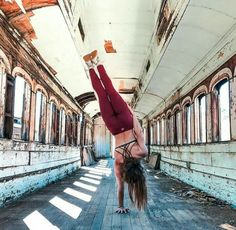 a woman is doing a handstand in an old train car with no one around her