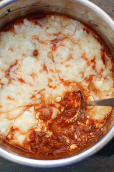 a pot filled with sauce and cheese on top of a table