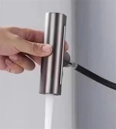 a person is opening the door with a handle on a white wall and black cord