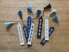 four blue and white tassels on a wooden floor with one tied up to the side