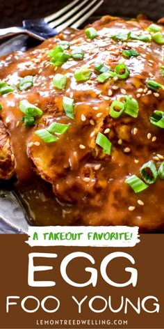 an egg covered in gravy and topped with green onions on a black plate