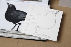 two black birds sitting on top of paper next to some scissors and other art supplies