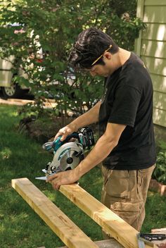 a man is using a circular saw to cut wood planks with a power tool