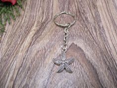 a silver starfish keychain sitting on top of a wooden table next to flowers