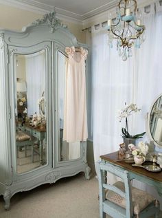 a room with a dresser, mirror and chandelier in it's corner