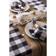 the table is set with black and white checkered napkins, silverware, and gold - plated utensils