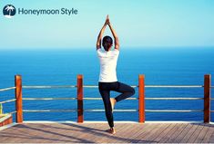 a woman is doing yoga on a deck overlooking the ocean with her hands in the air