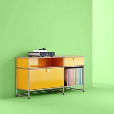 a yellow cabinet with records on it against a green wall