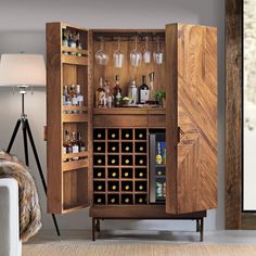 an armoire with wine glasses and bottles in it is next to a couch that has a rug on the floor