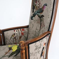 a chair with birds and flowers on the back is upholstered in wood frame