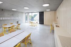 an empty room with tables and chairs in the center is lit by recessed lights