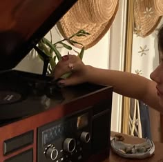 a woman with her hand on the top of a record player and looking at it