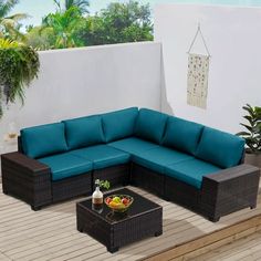 a blue couch sitting on top of a wooden floor next to a table and potted plant