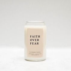 a candle with the words faith over fear printed on it in black and white font