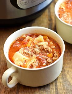 two white bowls filled with soup next to an electric pressure cooker on a wooden table