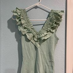 a green tank top hanging on a hanger