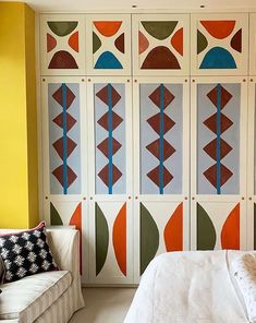 a bed sitting next to a white couch in a room with colorful wallpaper on the walls