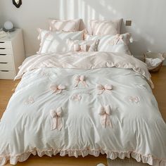 a white bed with pink bows on the comforter and pillow cases in a bedroom