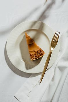 a piece of pie on a white plate with a gold fork and napkin next to it